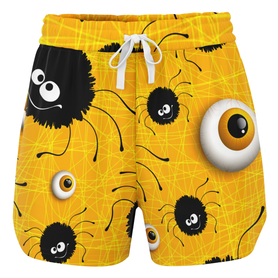 Front view of yellow shorts laid flat, showing a pattern of cartoon spiders and eyeballs with a white drawstring.
