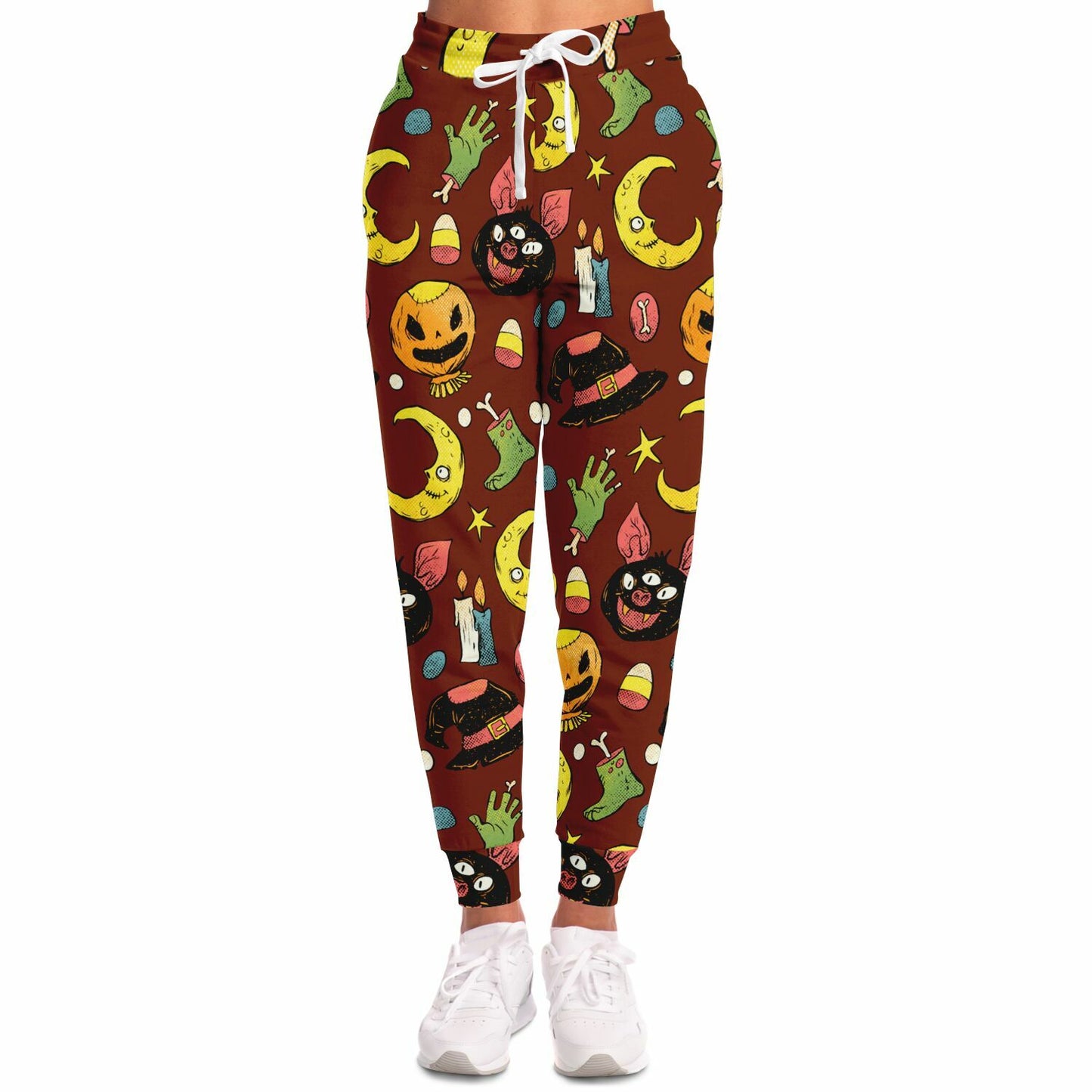 Front view of a woman wearing brown joggers with a colorful Halloween pattern and white sneakers.
